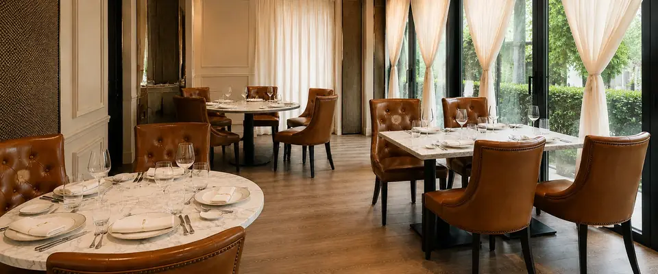 Round and rectangular marble tables with tan leather seating beside the windows at CALI Raffles Place.