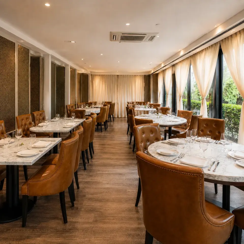 The open dining room at CALI Raffles Place — marble tables, tan leather chairs and natural light.