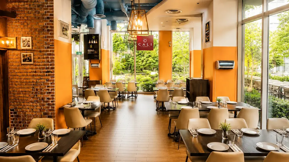 Glass-walled dining room and full bar at CALI Rochester Park
